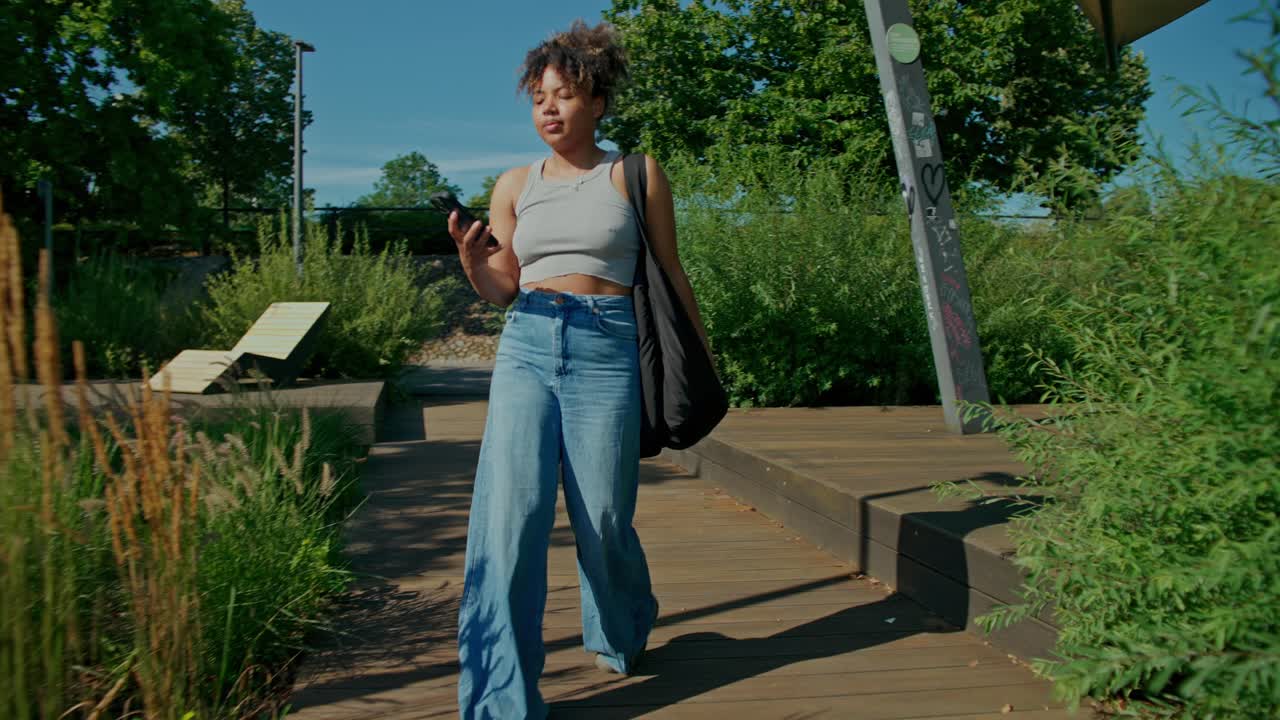 Giovane donna che usa il cellulare in un parco urbano