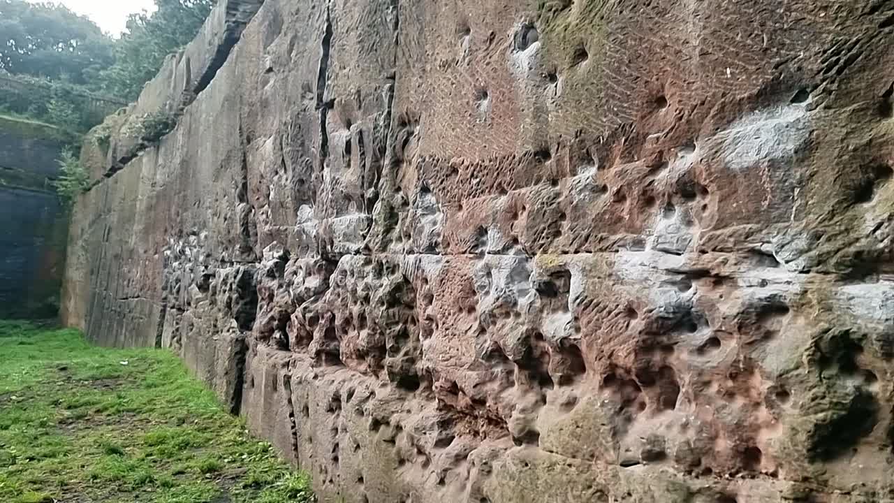 Chalk covered textured rock climbing gripping holes in steep quarry rock wall surface, Slow right pan close up