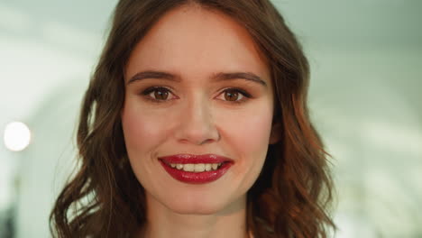 mujer feliz con brillo de labios brillante mira a la cámara sonriendo