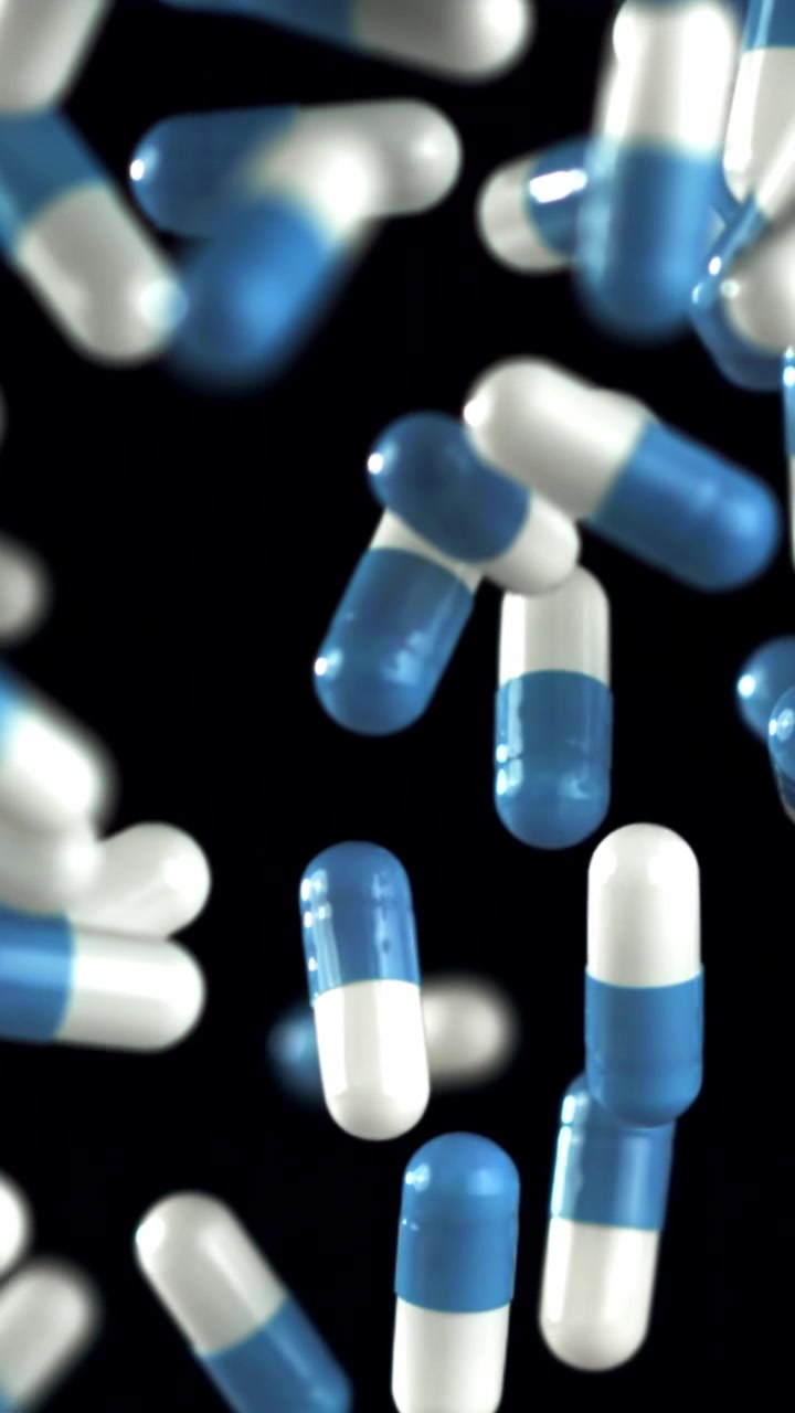 Capsule blu e bianche che cadono al rallentatore su sfondo nero