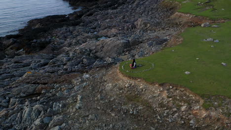 tranquil coastal scene of man meditating in desolate landscape