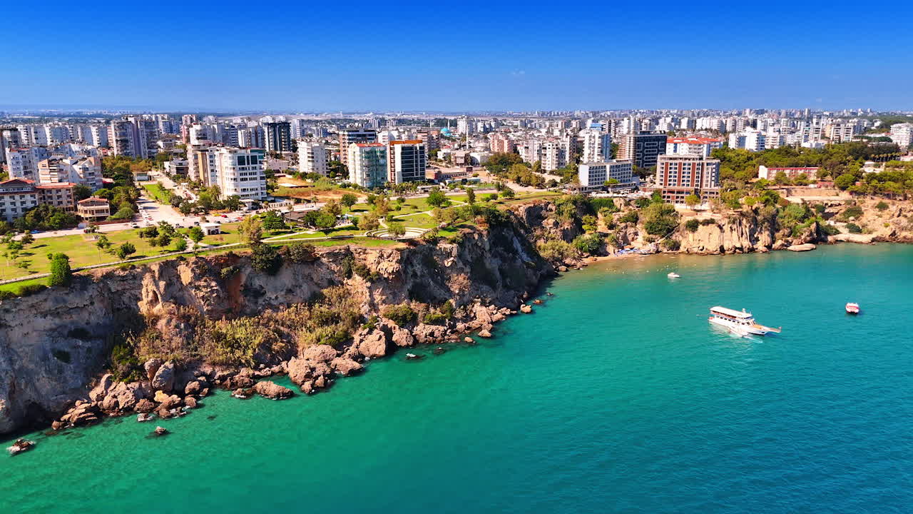 Beautiful rocky shore of Antalya, Turkey. Some boats are on the water. Modern cityscape of the city from top view