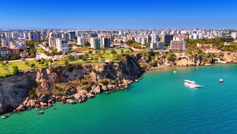 beautiful rocky shore of antalya, turkey. some boats are on the water. modern cityscape of the city from top view