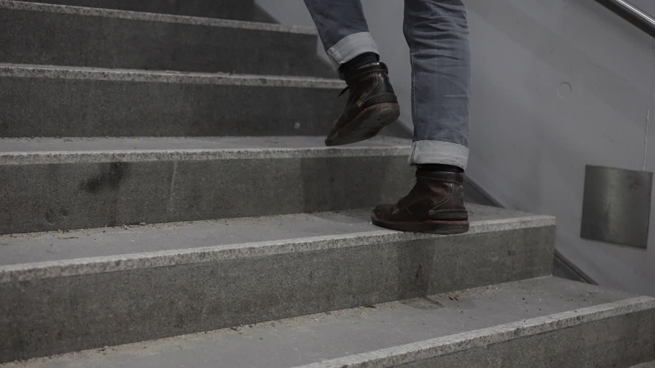 Tracking shot of footsteps of man, wearing jeans and boots climbing stairs. Follow through shot