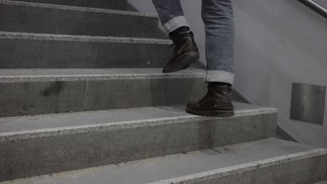 tracking shot of footsteps of man, wearing jeans and boots climbing stairs. follow through shot