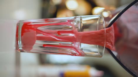 a barista pours a milk and strawberry cocktail into a glass slow motion , vertical video