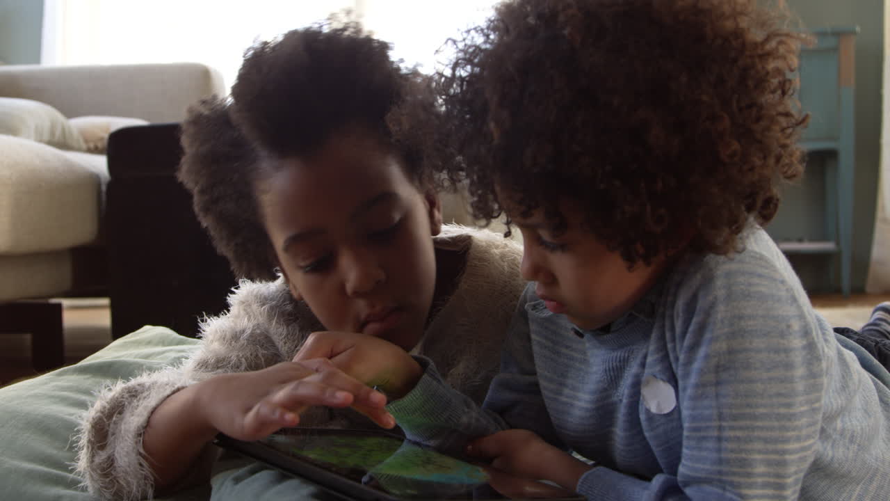 Due bambini giocano con un tablet a casa, registrato su R3D