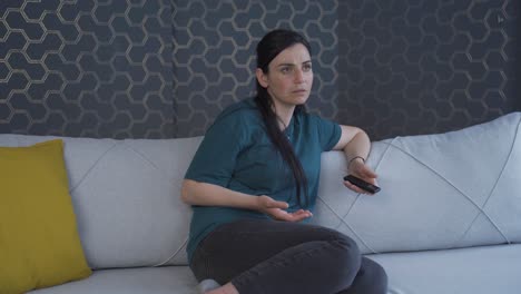 la mujer mirando fijamente la televisión con asombro.