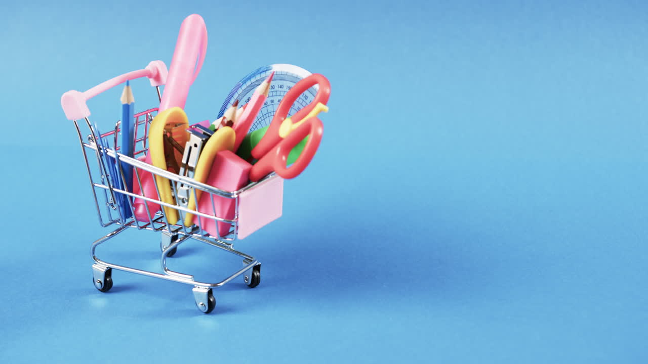 학교 물건과 파란색 배경에 복사 공간을 가진 쇼핑 트롤리의 클로즈업