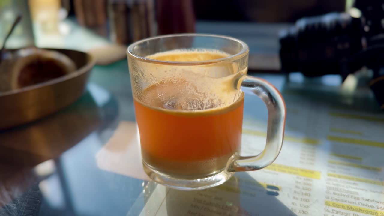 Closeup of clear glass mug with vibrant orange sea buckthorn tea