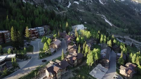 a drone flight over a small village like ski resort in the mountains of utah as the sun rises in spring