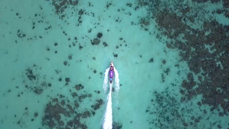 vista de 4k desde arriba, impresionante toma aérea siguiendo un bote de cola larga en un mar turquesa y claro, islas phi phi, tailandia, rodeada de agua
