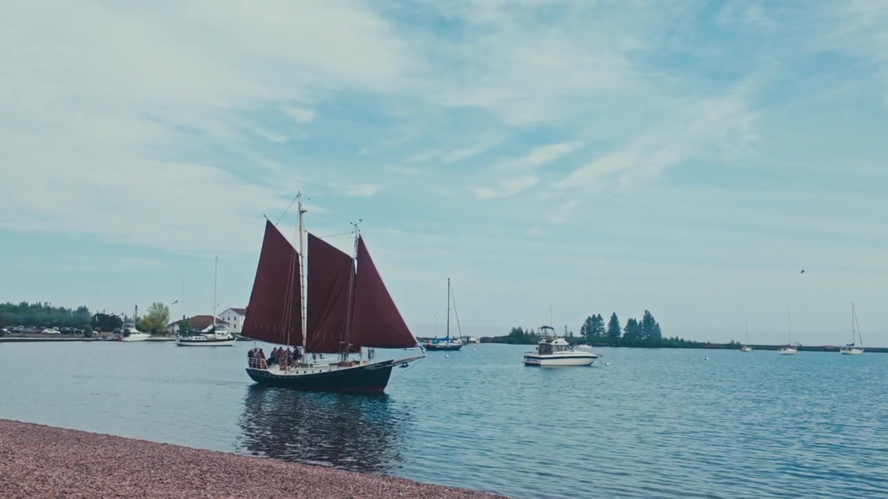 Il porto di Grand Marais mentre un veliero d'epoca passa davanti alla spiaggia in una luminosa giornata estiva