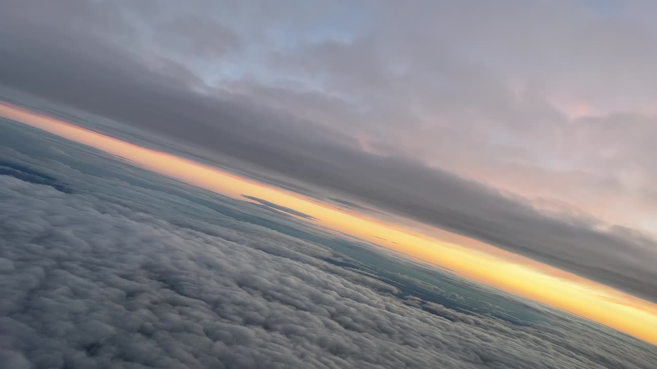 punto de vista del piloto desde la cabina de un jet durante un giro a la izquierda al amanecer mientras volaba entre capas de nubes con un cielo ogange