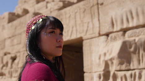 woman standing at ancient egyptian temple in dendera, facing the stone walls