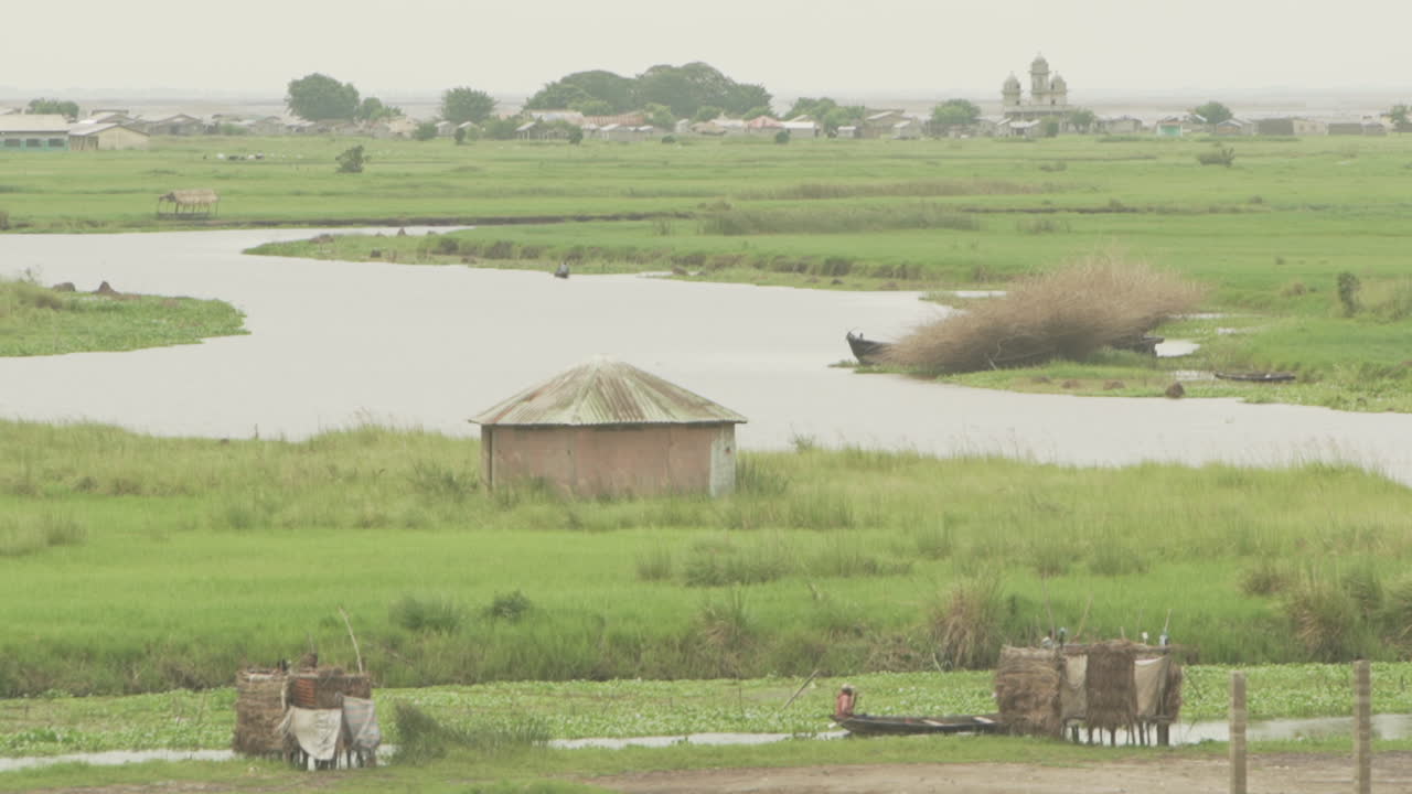 Canoe and Gondolier on river with mosque in background in Benin
