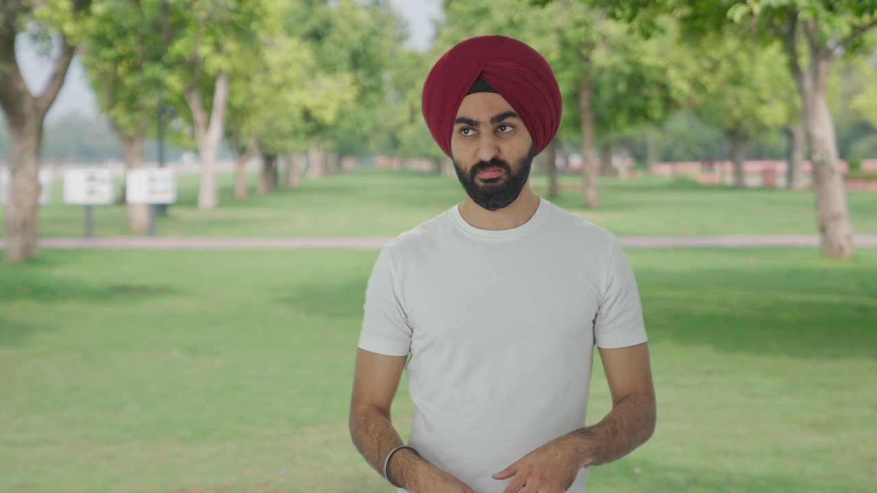 Uomo indiano Sikh frustrato che fa volare una zanzara nel parco