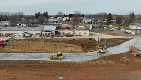 heavy machinery operates at a construction site in a rural area, moving earth and preparing the land for future development and infrastructure improvements.