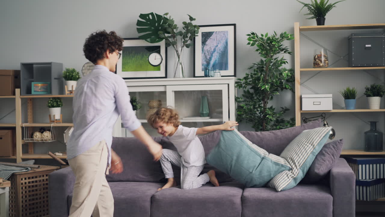 Mother and Son Having a Fun Pillow Fight at Home