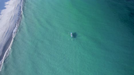 una toma aérea de un bote salvavidas de surf remando por la costa