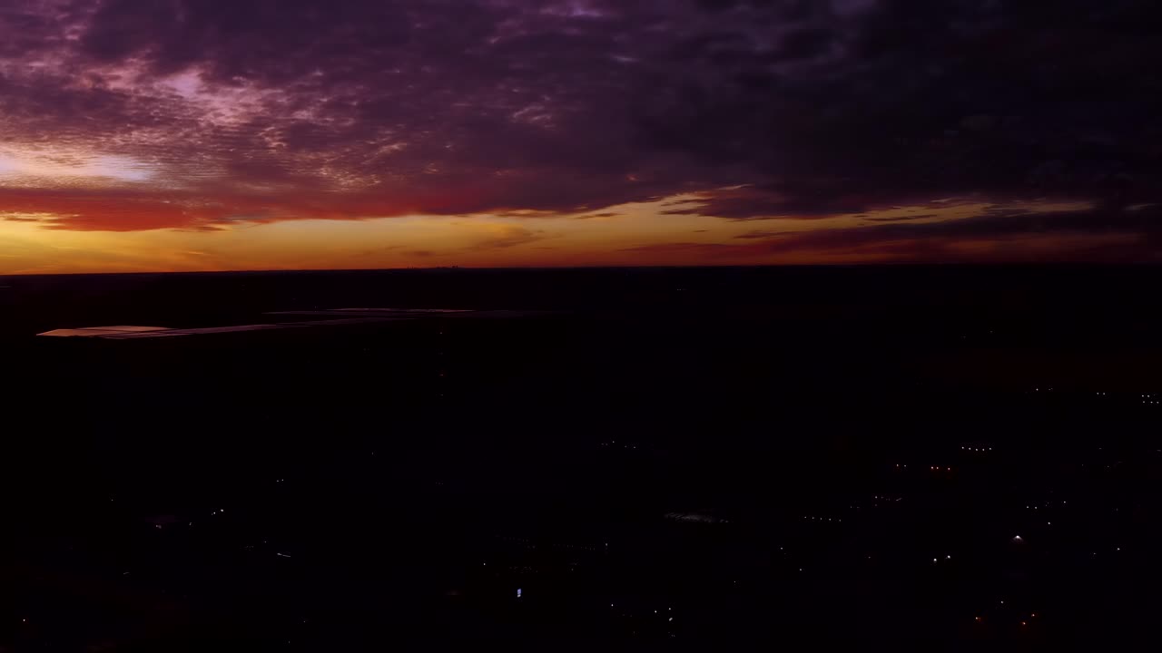 Amazing boundless coloured evening clouds float lit by setting sun light.  Canadian prairie nature landscape sunset.  Aerial pan up.