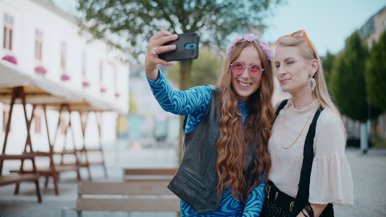 dos mujeres tomando una selfie en una plaza de la ciudad