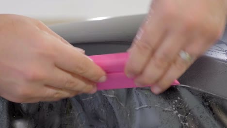 applying pressure to car wrapping foil with a squeegee tool, close up