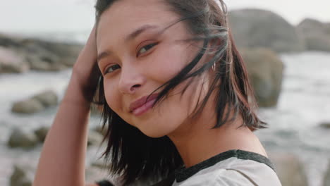 portrait of beautiful asian woman smiling enjoying cloudy seaside exploring vacation lifestyle with wind blowing hair on beach