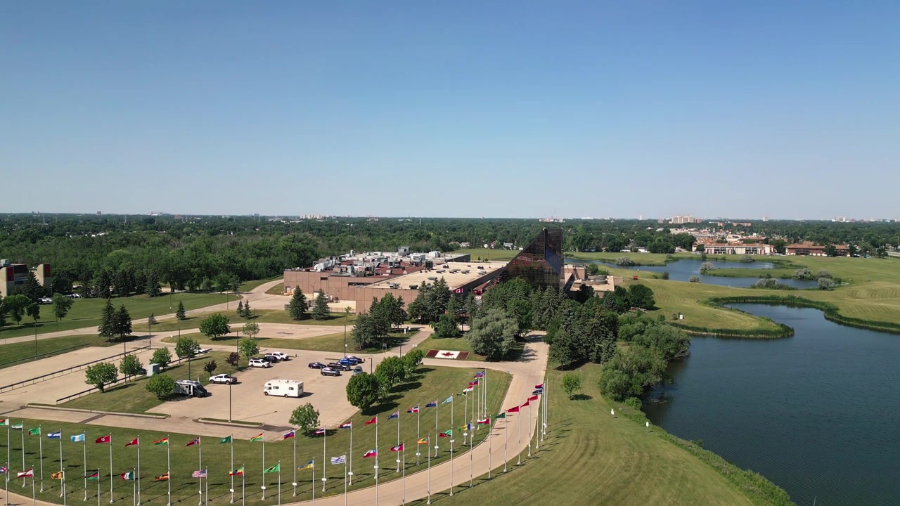 Ripresa aerea lenta in discesa con drone della Zecca Reale Canadese, con lo skyline di Winnipeg e i terreni circostanti visibili in una luminosa giornata estiva.