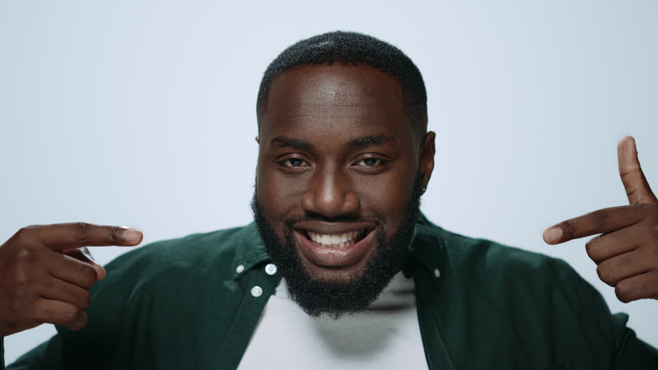 Portrait of african american man making funny faces in light background.