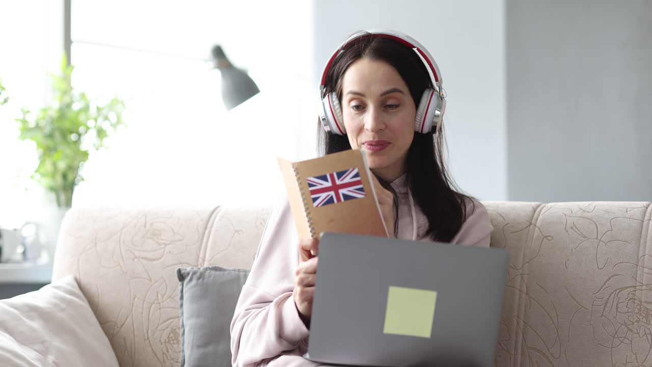 Woman learning English online with headphones and laptop at home