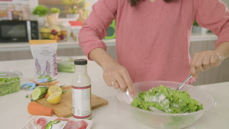 plano medio de una mujer mezclando todos los ingredientes de su ensalada