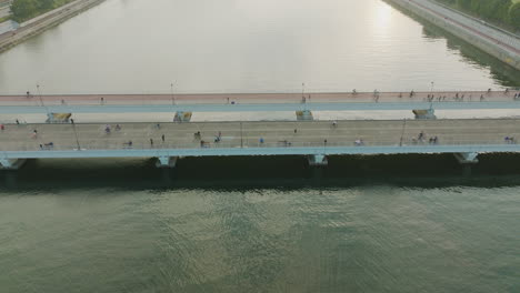 areal shot of people on a bridge over a river on a gloomy day