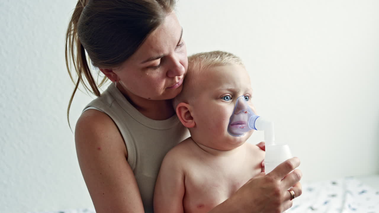 Therapeutic inhalation with a mask on the child's face. The child breathes through a nebulizer with cough medicine. Treatment of the child at home. Inhalation of the child at home