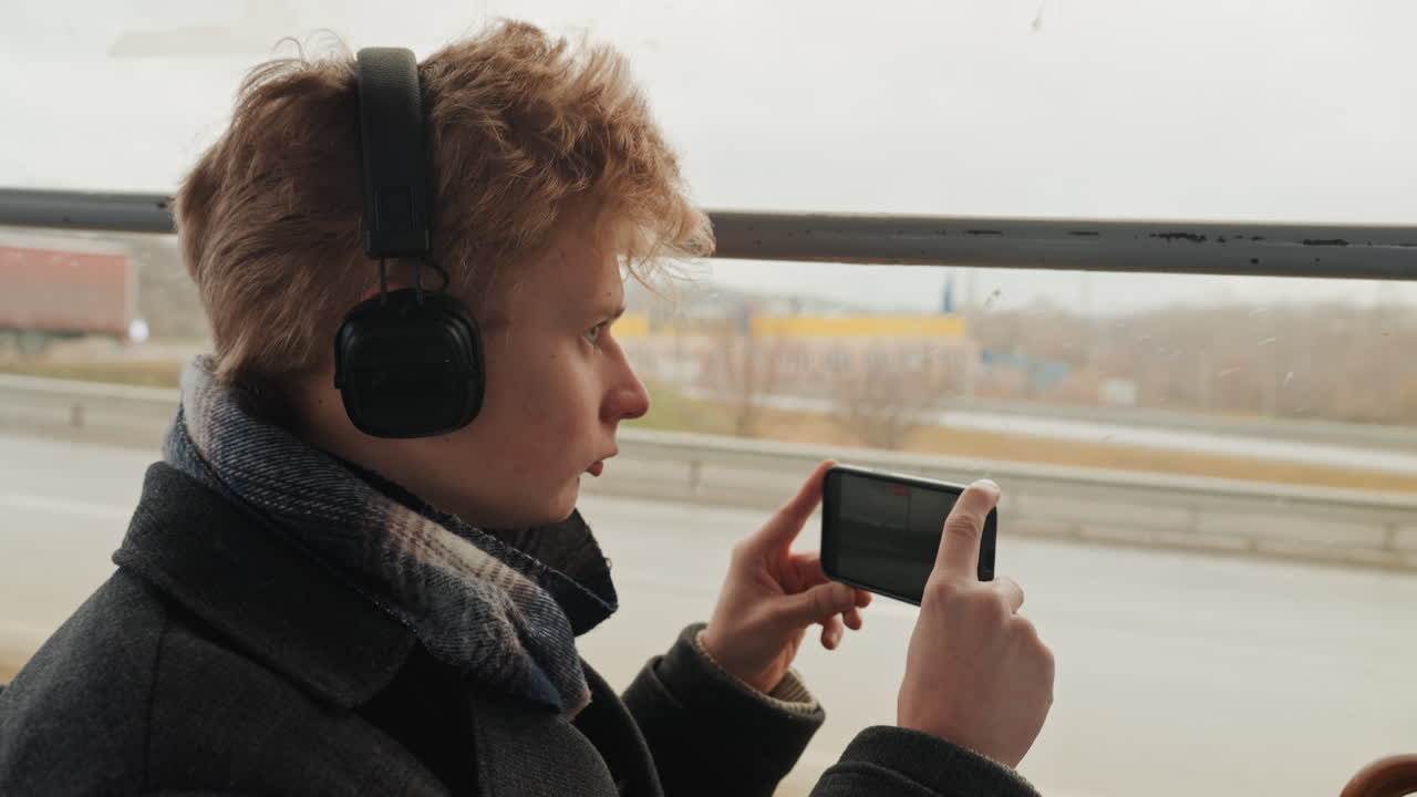 Persona che filma momenti di viaggio panoramici. Creatore che documenta esperienze di viaggio tramite registrazioni video mobili. Viaggiatore che cattura riprese dinamiche di paesaggi e città durante i viaggi in veicolo.