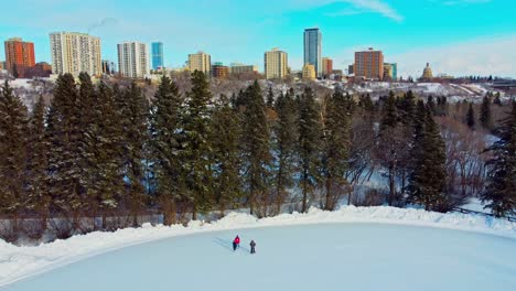 torres residenciales con vista al parque victoria pista de patinaje sobre hielo de invierno rodeada de pinos altos y parejas de citas dobles soportan el clima frío calentándose mutuamente y patinando personas al azar de edm4-4