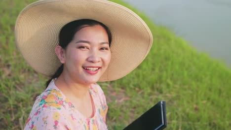 adult woman sitting and smile on the lawn using portable technology