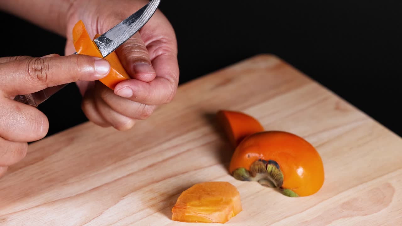 Hænder skærer forsigtigt en moden persimmon
