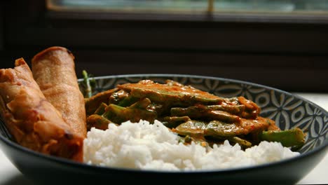 sartén cinematográfica de curry rojo tailandés vegano con rollos de primavera y arroz