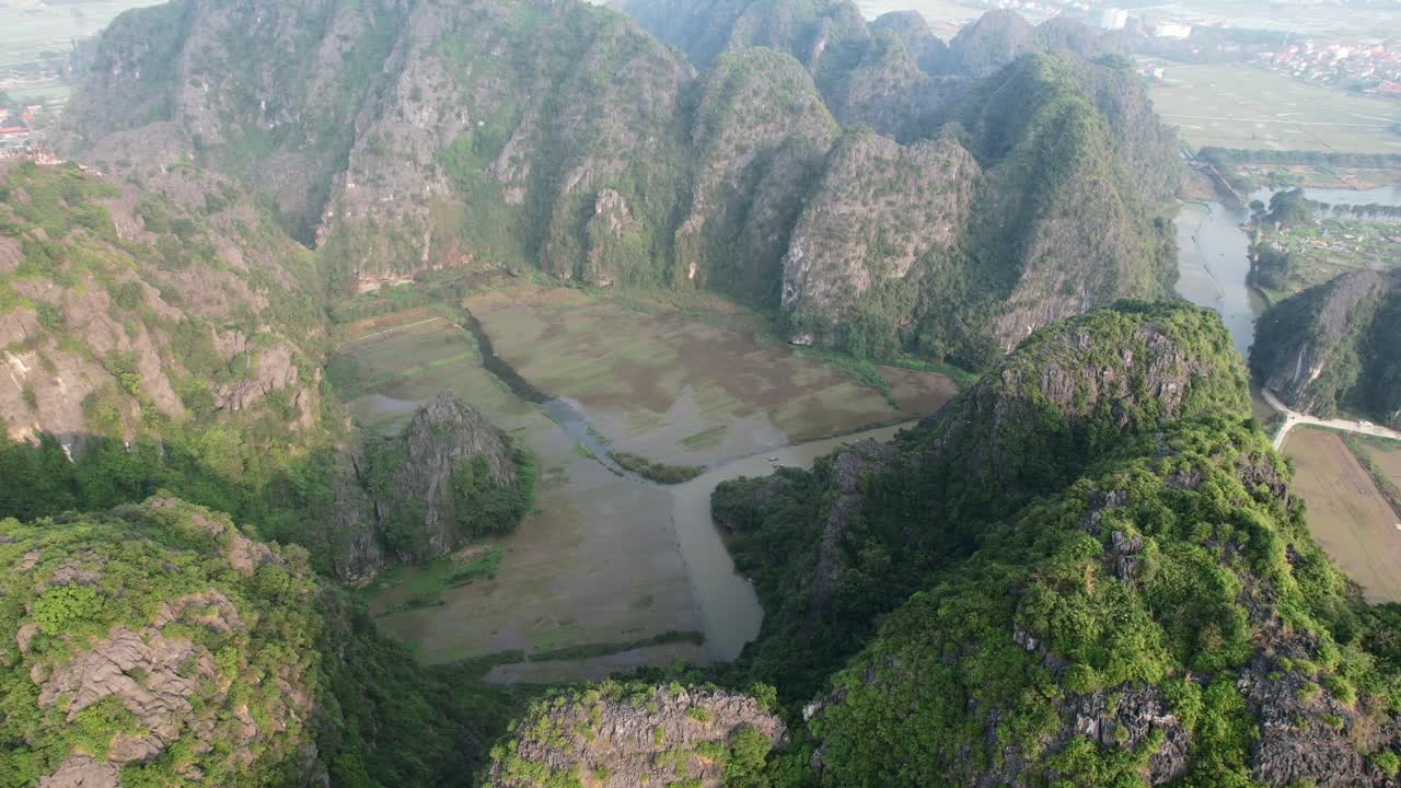 órbita aérea alrededor del río ngo dong y las empinadas cadenas montañosas de piedra caliza en el parque nacional de ninh binh, vietnam