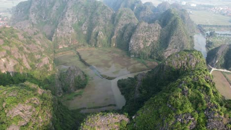 aerial orbiting around ngo dong river and limestone steep mountain ranges in ninh binh national park, vietnam