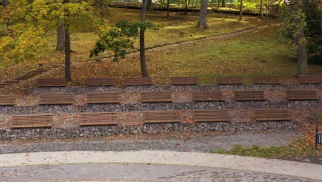 many benches form amphitheater in local park with autumn colors, dolly forward