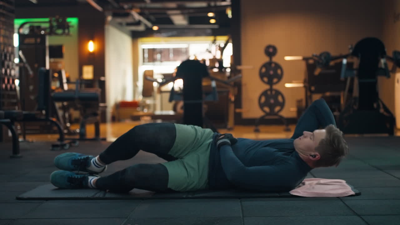 Sporty Man Exercising Twisted Crunch or Twisting Crunch in Modern Gym - core exercise that combines a traditional crunch with a twisting motion, targeting the obliques and other abdominal muscles side