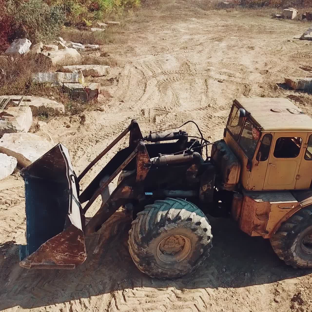 specially machinery with a bucket for picking stones is working in a quarry near the hill with forest. Close-up