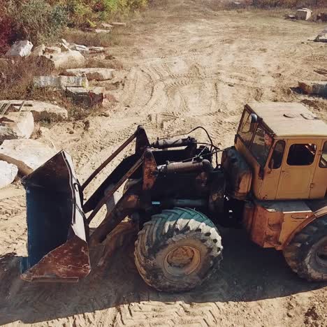 specially machinery with a bucket for picking stones is working in a quarry near the hill with forest. close-up