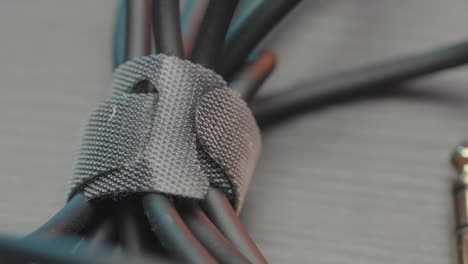 close up of an acoustic cable lying on wooden table surface. action. rolled audio jack cable, details of professional equipment