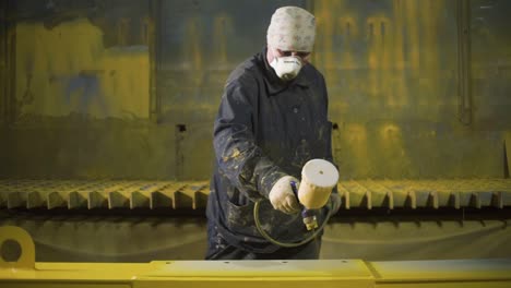 industrial worker spray painting metal parts