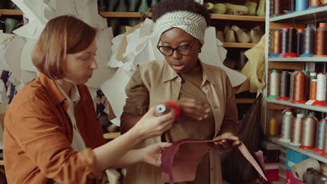 female coworkers choosing thread in workshop