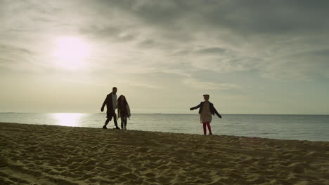 cheerful family going beach sunset sky ocean. people group walk on sea coast.