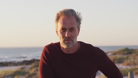 retrato de un hombre caucásico feliz dirigiéndose a la cámara y sonriendo en un día soleado en la playa